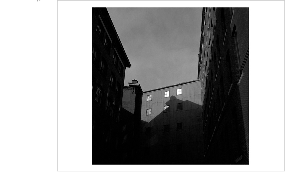 In this valley of shade in downtown Boston, the light strikes five windows.