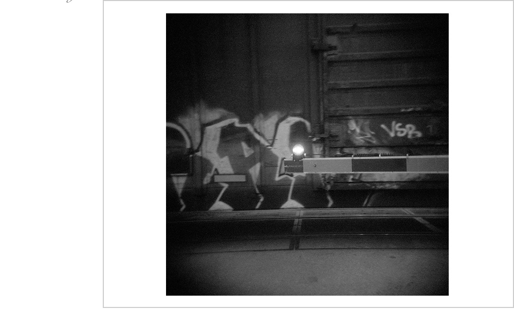Graffiti covered train slows down just enough at the crossing.