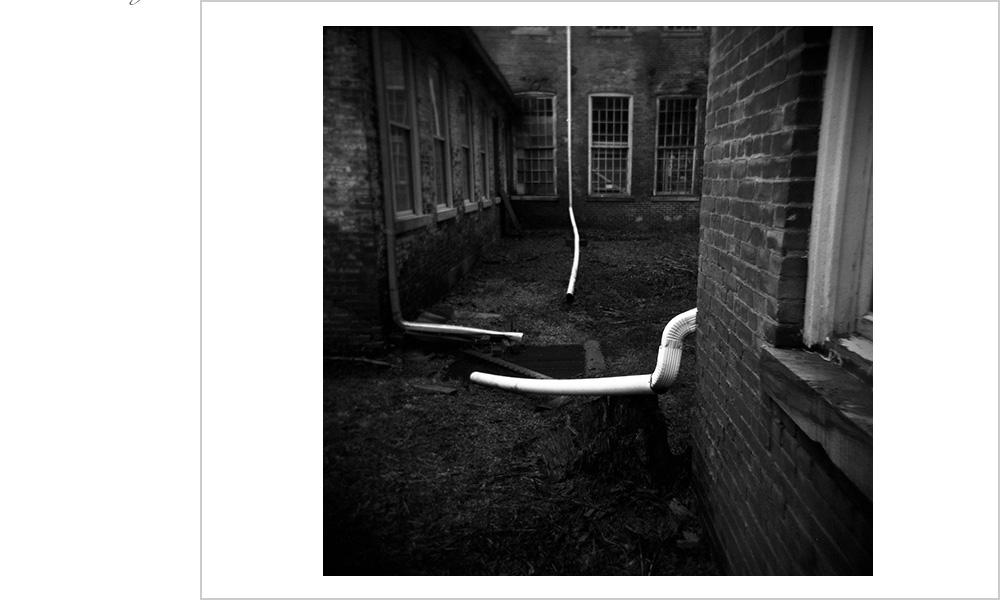 Three downspouts from three buildings have a secretive meeting of the royal order of water conveyance.