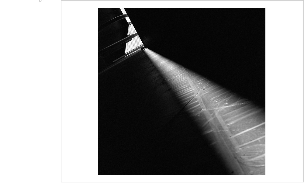 A subtle shaft of light trickles from above illuminating the textured wall and the incredible talents of the photographer